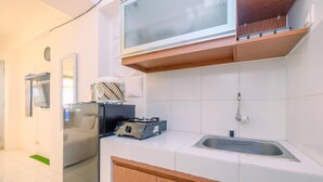 A modern kitchen with white tiles, a stainless steel sink, wooden cabinets, and a built-in microwave.