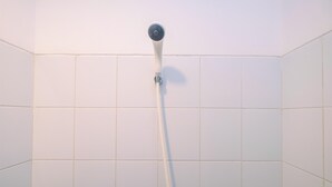 A showerhead mounted on a tiled wall in a bathroom.