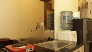 A kitchen with a sink, a red appliance, a water dispenser, and a refrigerator.