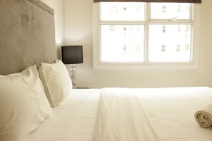 Relax in a cozy retreat with a comfortable bed, bedside lamp, and stunning city view.