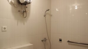 A bathroom with white tiled walls, a shower with a handheld showerhead, a towel rack, and a power outlet. - Homey and Chic 2BR Apartment Newton Residence (Bandung)