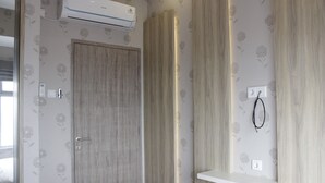 A modern bathroom with a wooden door, a white sink, and a wall-mounted air conditioner. - Homey and Chic 2BR Apartment Newton Residence (Bandung)