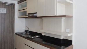 A kitchen with a black countertop, white cabinets, and a stainless steel sink. - Spacious Studio Room at Galeri Ciumbuleuit 3 Apartment (Bandung)