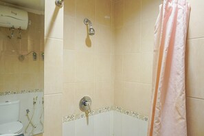 Et badeværelse med bruser, toilet og vandvarmervarmere.