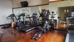 Une salle de sport équipée de divers appareils d’exercice, notamment des tapis de course, des vélos d’appartement et des appareils de musculation elliptique.