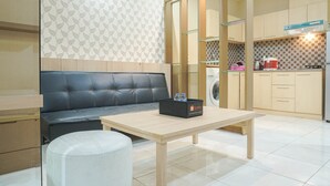 Un espace de vie compact comprenant un canapé, une petite table, un lave-linge et une kitchenette.