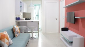 A modern living room with a light blue sofa, a white coffee table, and a TV mounted on a red wall.