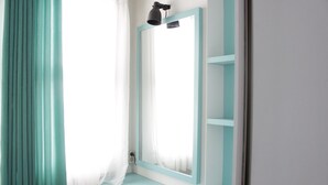 A bathroom with a light blue vanity, a mirror with a light blue frame, and a white shower curtain.