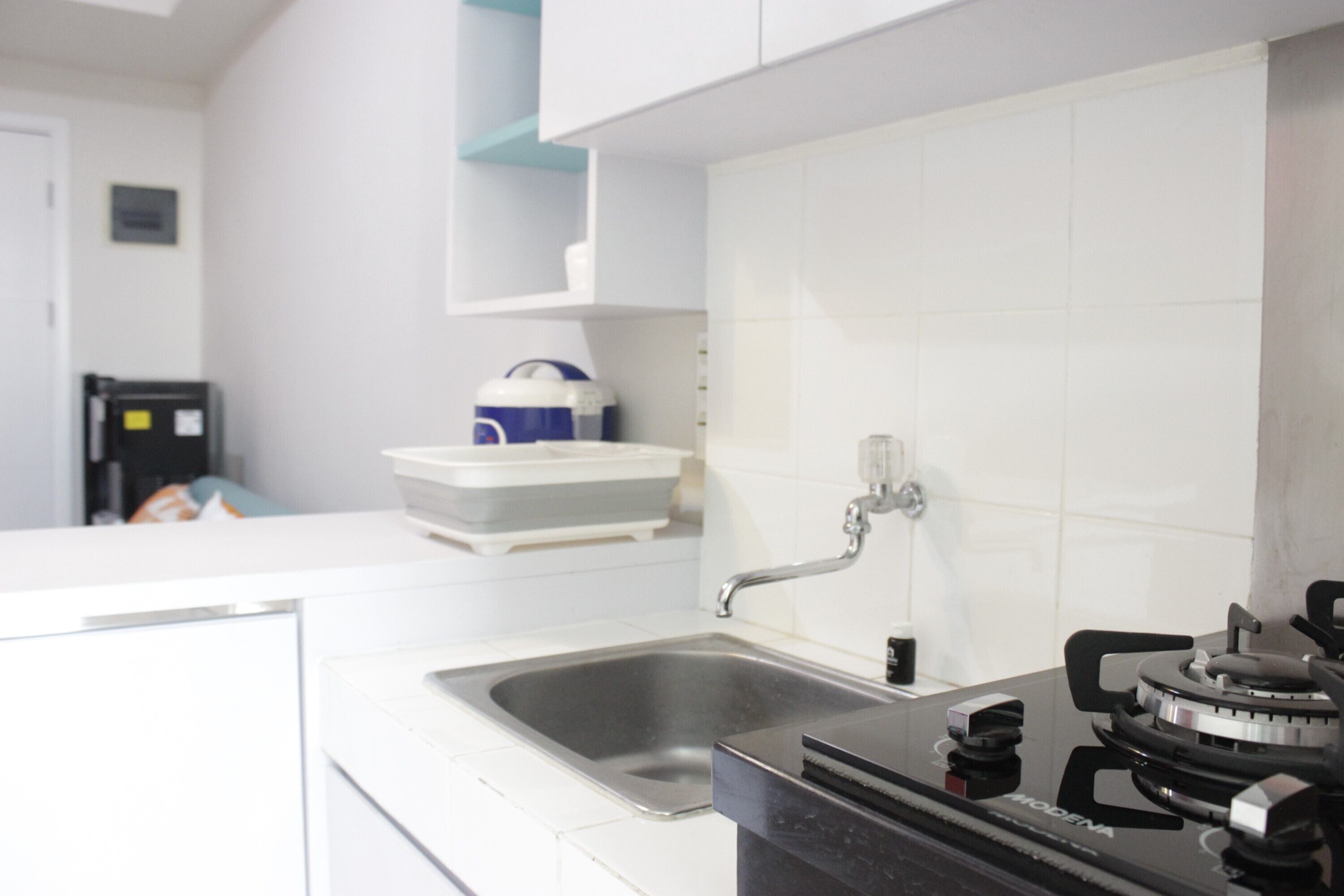 A modern kitchen with a stainless steel sink, a gas stove, and white cabinetry.