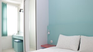 A bedroom with a bed, a desk, and a wardrobe.
