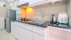 A modern kitchen with white cabinets, a stainless steel sink, a kettle, and a rice cooker. - Furnished Green Pramuka 1BR Apartment with Modern Style and City View (Jakarta)