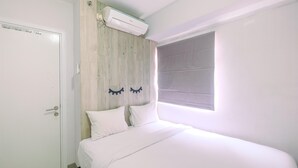 A bedroom with a bed, a white door, a wooden headboard, and a window with blinds. - Furnished Green Pramuka 1BR Apartment with Modern Style and City View (Jakarta)