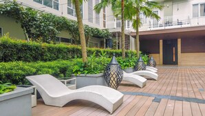 Un patio con sillones de descanso, plantas en macetas y una terraza de madera.