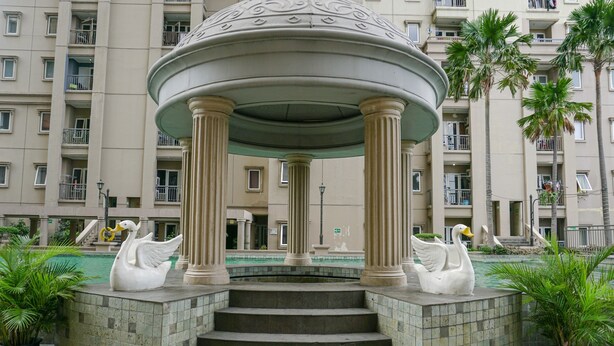A gazebo with swan statues, steps leading up to it, and a pool in the background. - Spacious 3BR Residence at Grand Palace Kemayoran Apartment (Jakarta)