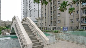 A staircase leading to a building with a pool and a signboard. - Spacious 3BR Residence at Grand Palace Kemayoran Apartment (Jakarta)