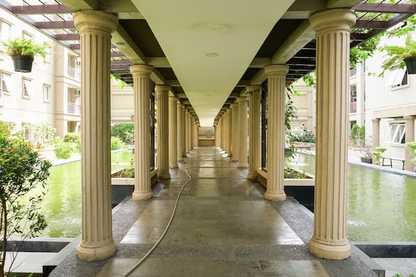 Un couloir orné de colonnes, agrémenté d’un élément décoratif aquatique et de plantes suspendues.