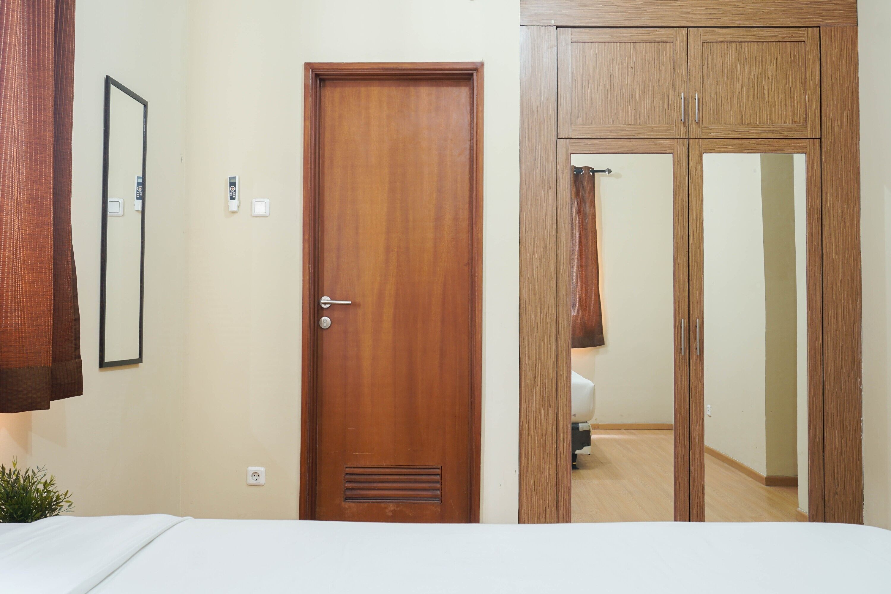 Un dormitorio con puerta de madera, espejo y armario.