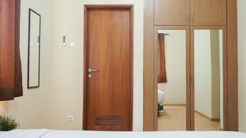 Un dormitorio con puerta de madera, espejo y armario.