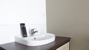 A white bathroom sink with a dark wooden countertop, a silver faucet, and a black soap dispenser. - Spacious 2BR Apartment Gateway Pasteur near Exit Toll 23 (Cimahi)