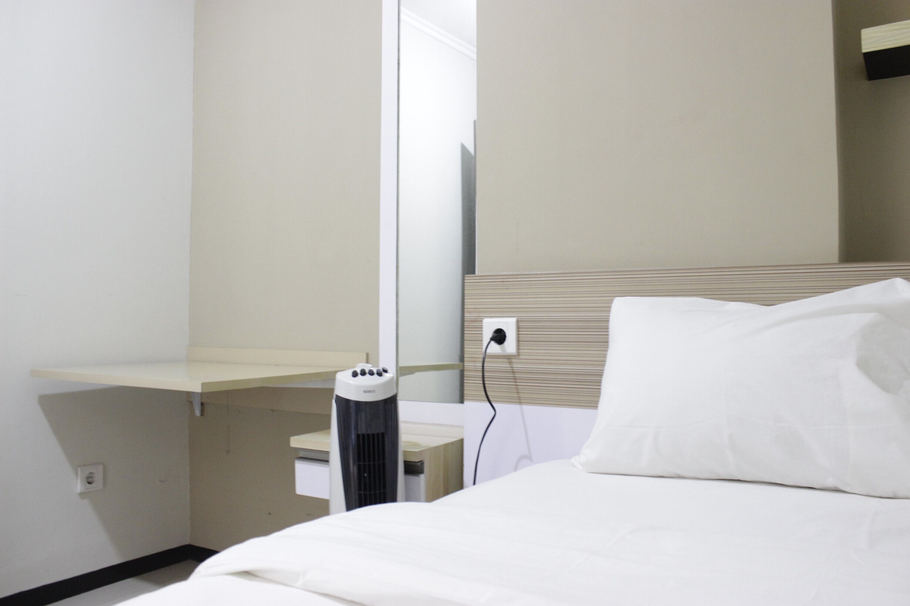 Ein Hotelzimmer mit einem Bett, einem Nachttisch, einem Heizgerät und einer Wandsteckdose.