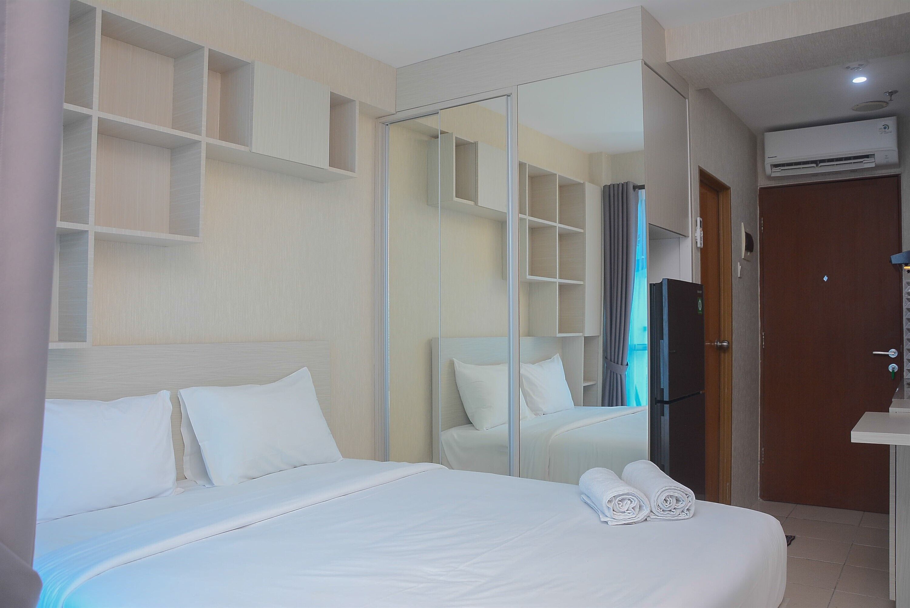 A hotel room with a bed, a mirror, a wardrobe, and a bathroom.