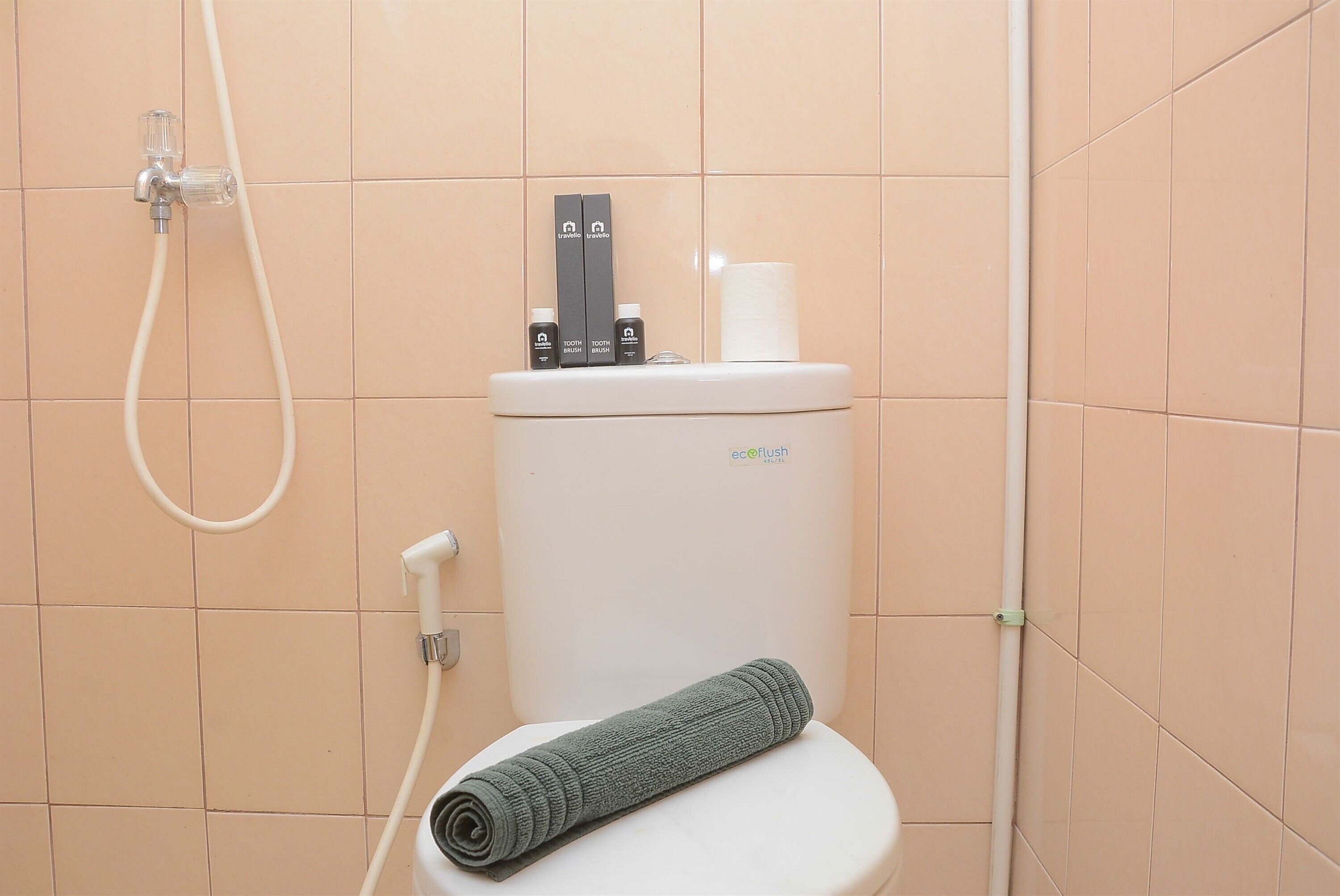 Ein Badezimmer mit Toilette, Duschschlauch und Handtuch auf dem Sitz.