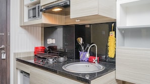 Een moderne keuken met een zwart aanrecht, een roestvrijstalen spoelbak en houten kastjes.