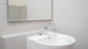 Een witte badkamer met een wastafel, spiegel en betegelde wanden.