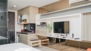 Een moderne hotelkamer met een bed, een televisie, een kitchenette en een spiegel.