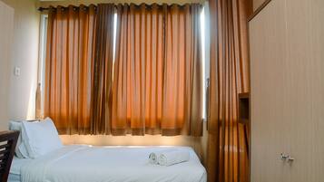 Una habitación de hotel con una cama bien hecha, un cabecero de madera y un amplio ventanal con cortinas.