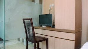 A small, private office space with a desk, chair, and a television. - Cozy and Minimalist Studio Apartment at Saladdin Mansion (Depok)
