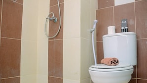 A bathroom with a toilet, a shower, and a towel. - Cozy and Minimalist Studio Apartment at Saladdin Mansion (Depok)