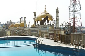 Ein Schwimmbad mit Blick auf eine Moschee mit goldenen Kuppeln und Minaretten.