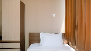 A hotel room with a bed, a wooden nightstand, and a window with curtains. - Cozy and Minimalist Studio Apartment at Saladdin Mansion (Depok)
