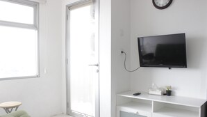 Ein modernes Schlafzimmer mit Bett, Fernseher, kleinem Tisch und einer Tür.