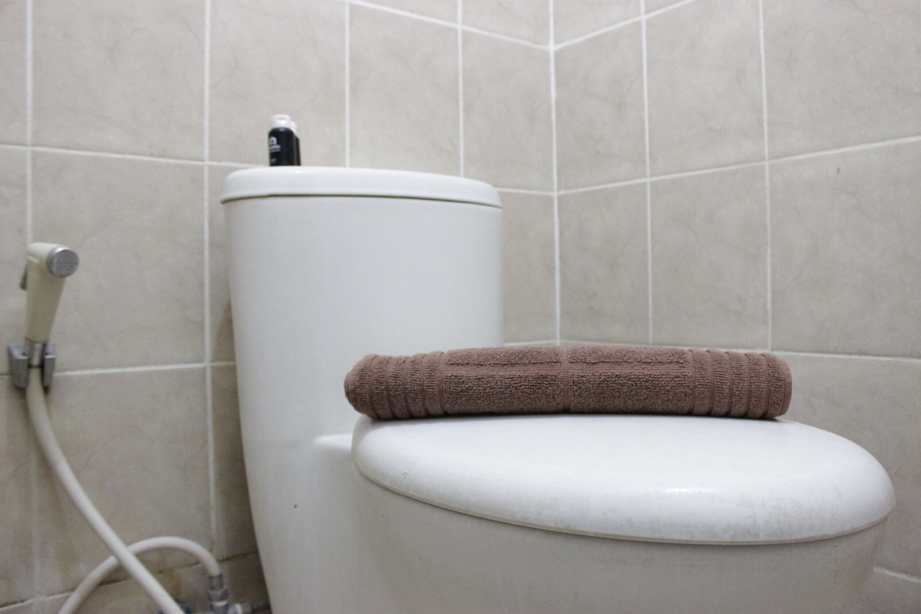 A toilet with a towel on the seat and a water heater on top.