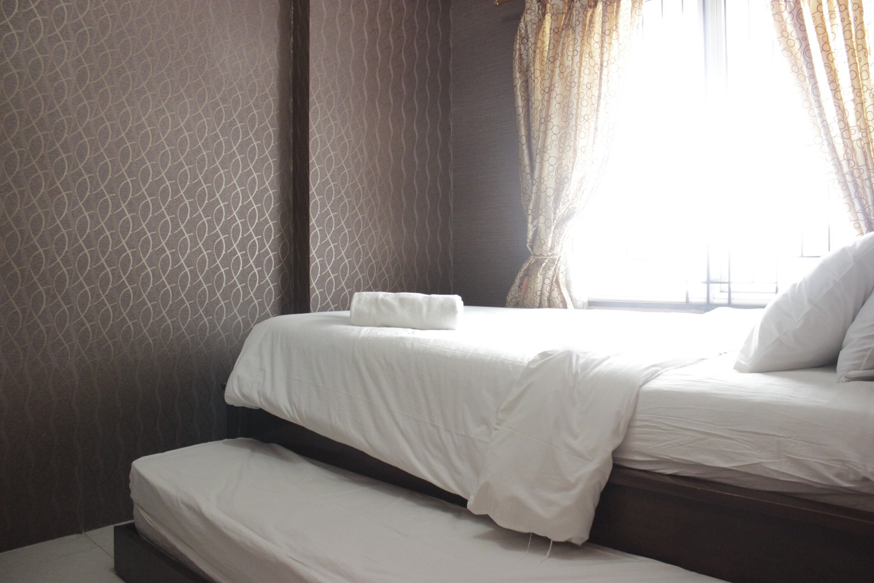 Habitación de hotel con dos camas, una ventana con cortinas y paredes con diseño.