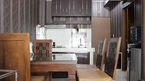 A kitchen with wooden cabinets, a stainless steel range hood, and a water dispenser. - Chic and Cozy 2BR Apartment at Pinewood Jatinangor near JATOS (Cileunyi)