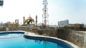 A rooftop swimming pool with a view of a golden-domed building and a tall communication tower. - Compact and Simple Studio Apartment at Saladdin Mansion (Depok)