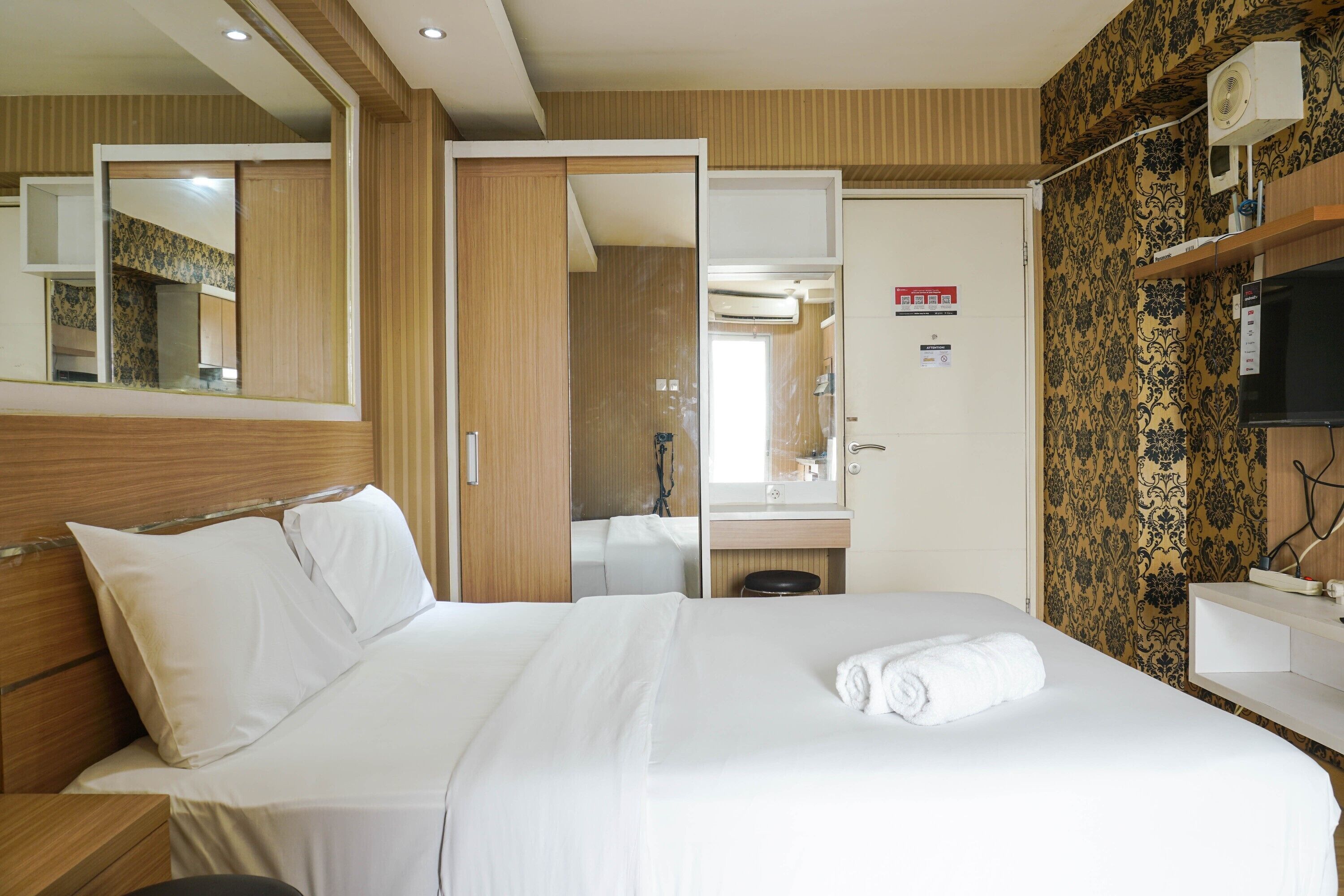 Een hotelkamer met een bed, spiegel, badkamer en televisie.