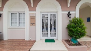 A building with a pink facade, white arches, and a green doormat.