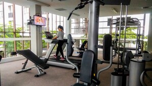 Ein Fitnessstudio mit Cardiogeräten, Gewichte und einem Fernsehbildschirm.