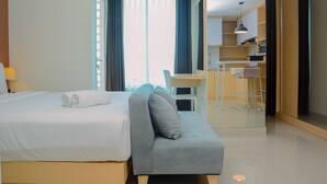 A modern hotel room with a bed, a sofa, a desk, and a kitchenette. - Grand Kamala Lagoon Studio Apartment with Modern Interior (Bekasi)