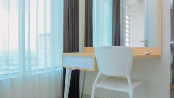 A modern room with a white desk, a chair, a large mirror, and sheer curtains.