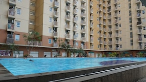 A swimming pool surrounded by a high-rise residential building with balconies. - Duri Kosambi Cozy and Relaxing 3BR Apartment at Green Palm Residence (Jakarta)