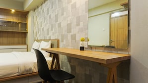 A hotel room with a bed, a desk, a chair, a mirror, and a wall with a geometric pattern. - Duri Kosambi Cozy and Relaxing 3BR Apartment at Green Palm Residence (Jakarta)