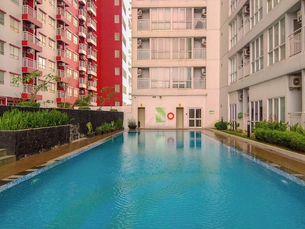 Une piscine entourée d’immeubles résidentiels à plusieurs étages, dotés de balcons.