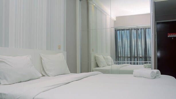A hotel room with a large bed, a glass partition, and a view of the outside.