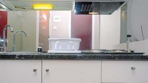 A kitchen with white cabinets, a granite countertop, a sink with a faucet, and a dish rack.
