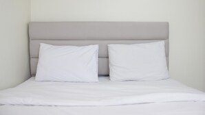 A bed with a grey headboard and two white pillows.